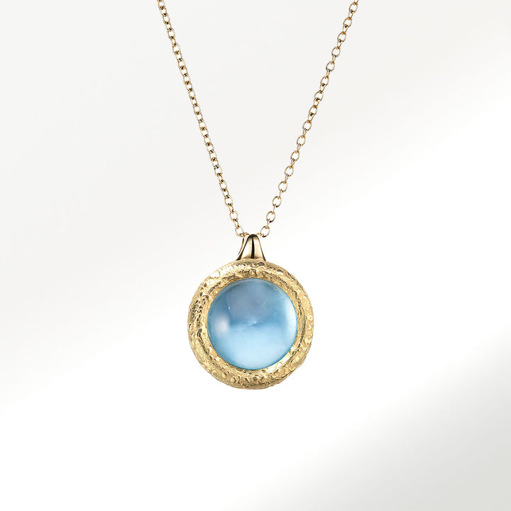 Collar Elena Carrera colección Fusión en oro de 18 quilates (750 milésimas), botón de 9mm con topacio azul natural, talla cabuchón sobre fondo de madreperla. Perfecto para disfrutarlo con todos tus estilismos. BY ELENA CARRERA