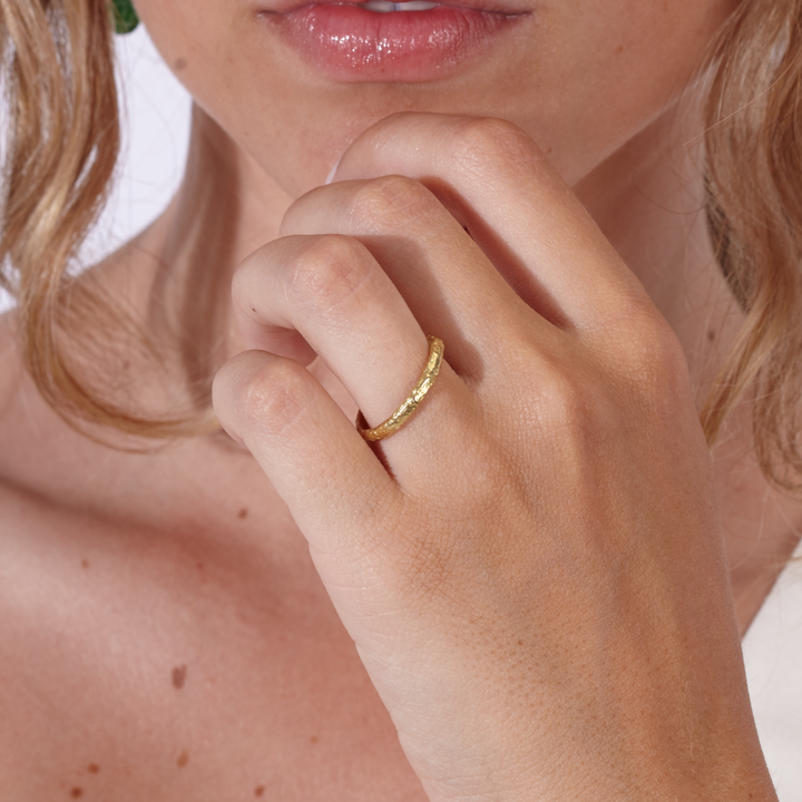Alianza de boda en oro amarillo 18k con textura arena puesta en modelo de By Elena Carrera