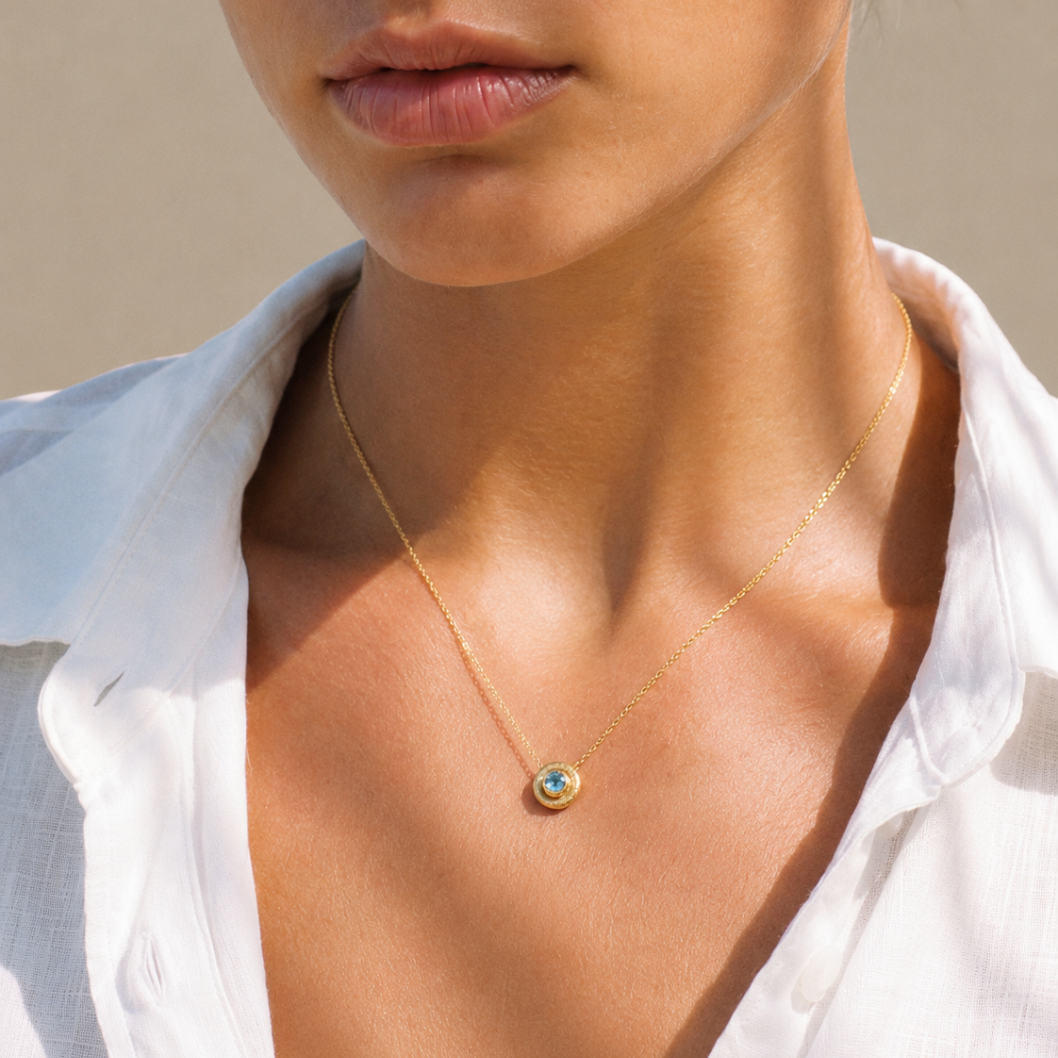 Mujer llevando colgante Bubbles de oro amarillo 18k con topacio azul natural