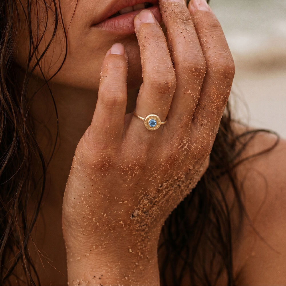 Modelo luciendo un anillo de topacio azul natural en oro amarillo 18k de la colección Bubbles