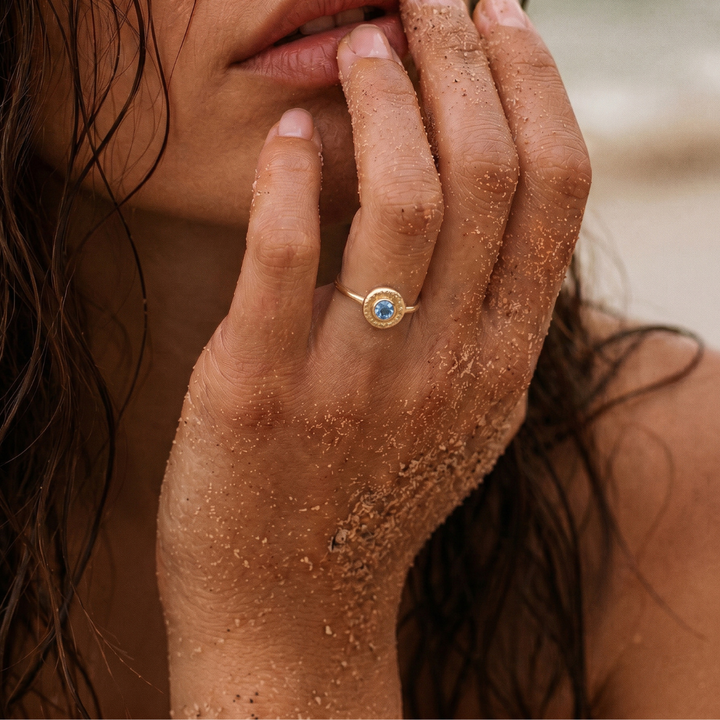 Modelo luciendo un anillo de topacio azul natural en oro amarillo 18k de la colección Bubbles