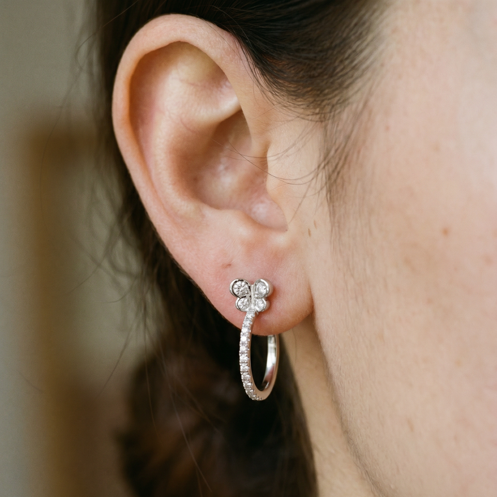 Modelo luciendo pendientes de aro de 13 mm en oro blanco de 18 quilates con mariposa y diamantes naturales
