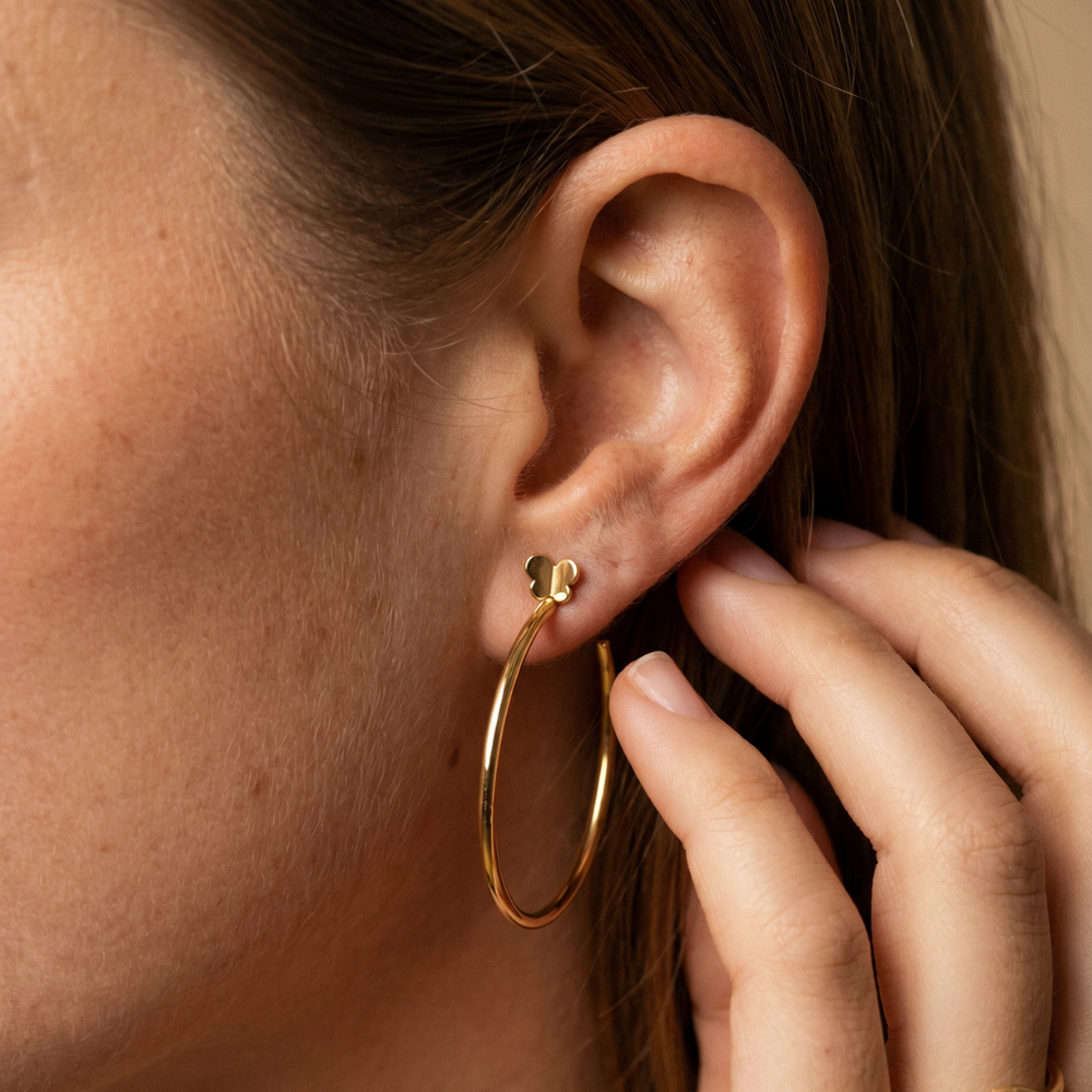 Modelo luciendo pendientes de aro en oro amarillo 18k con mariposa de la colección Hoops