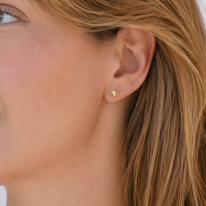 Modelo luciendo pendientes mariposa mini oro amarillo 18k