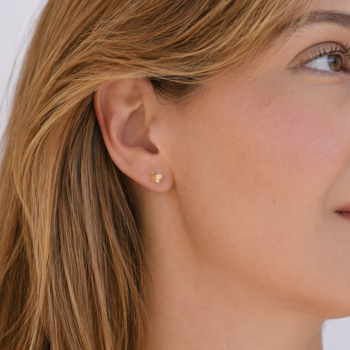 Modelo luciendo pendientes mariposa mini en oro rosa de 18 quilates con acabado textura arena