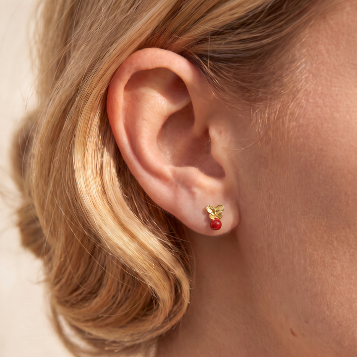 Modelo llevando los Pendientes Mariposa Mini de By Elena Carrera en oro amarillo 18k con coral mediterráneo natural